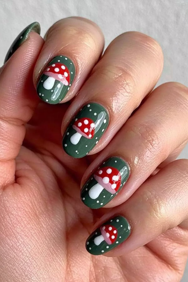 35 Whimsical mushroom nail art on a forest green base with tiny white speckles_bp